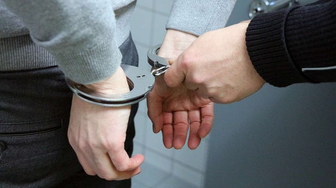 person putting handcuffs on another person
