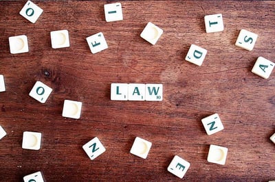 Scrabble pieces spelling law with others scattered across table