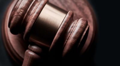 close up of bronze and wooden gavel resting on stand