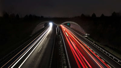 time lapse of cars on highway passing through tunnel at night