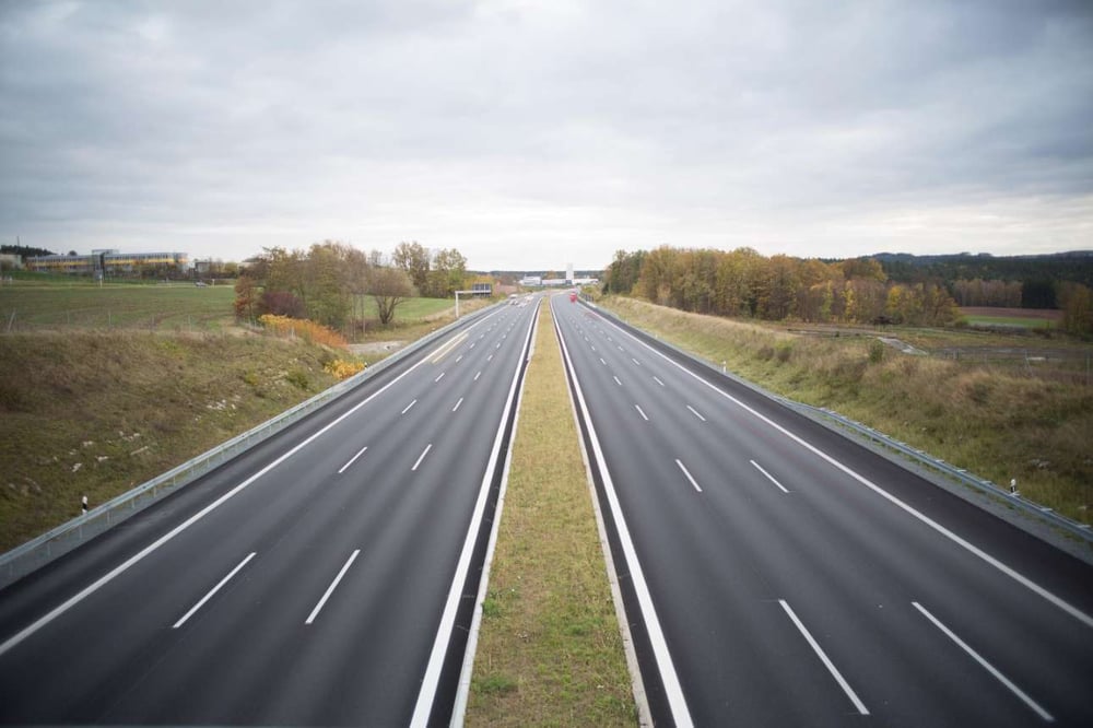 three lane highway in countryside disappearing into the distance