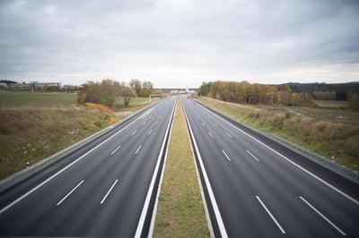 three lane highway in countryside disappearing into the distance