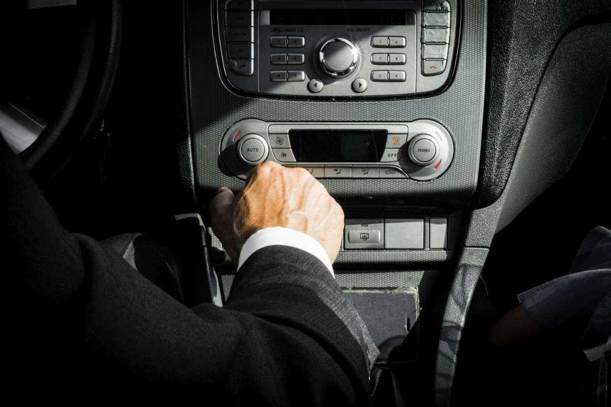 man in black suit driving and adjusting controls on dashboard