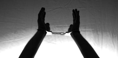 silhouette of two hands bound by handcuffs