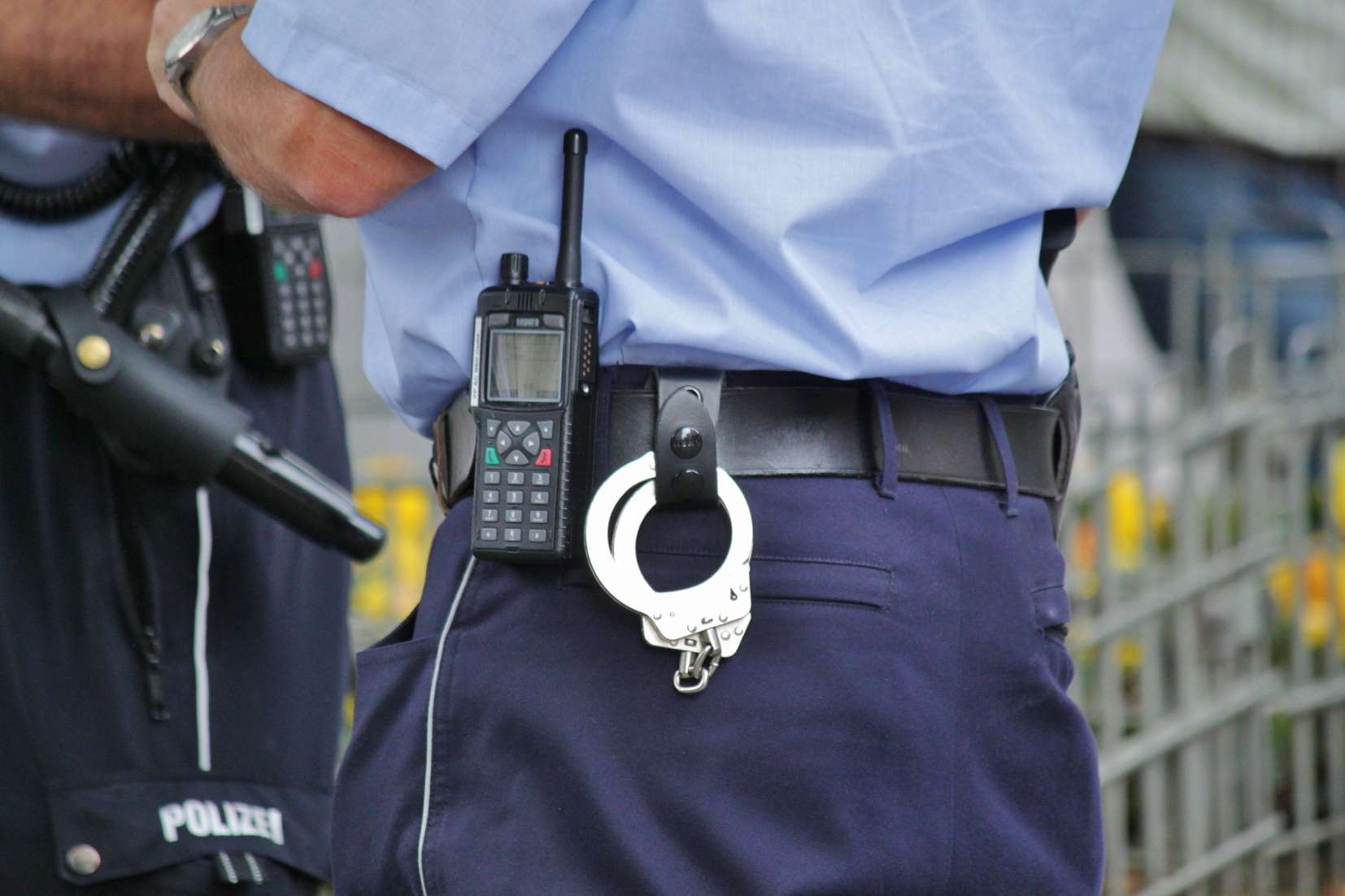 Waist of a police officer with handcuffs and pager on their belt