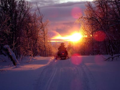 person on a snowmobile riding into the sunset