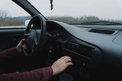 Person driving with one hand with drink in the cupholder